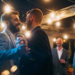 Hübsches glückliches schwules Paar feiert Hochzeit bei einer abendlichen Empfangsparty mit verschiedenen multiethnischen Freunden. Queere Jungvermählte tanzen und umarmen sich in einem Restaurant. LGBTQ-Beziehungsziele. – © gorodenkoff - istockphoto.com - 1391201571