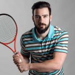 Konzentrierter Tennisspieler im Poloshirt mit Schläger mit beiden Händen, die auf ihren Dienst warten. – © panic_attack - istockphoto.com - 533353860