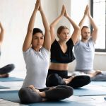 Diverse young people practicing yoga, young Indian woman wearing sportswear doing Padmasana exercise at group lesson, sitting in Lotus pose on mat, stress relief, working out in modern yoga center – © fizkes - istockphoto.com - 1198298331